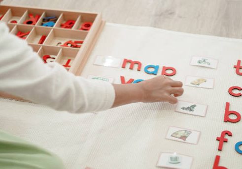 Elementary girl learning words and phonetic spelling using moveable alphabet in Montessori education school and homeschooling