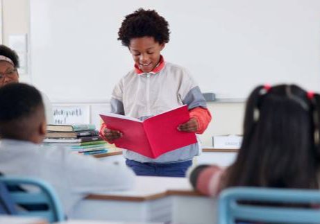 Class, child and reading presentation for learning, education or storytelling in elementary school. Kid boy, students and speech with teacher for assignment, project or knowledge with book in lesson